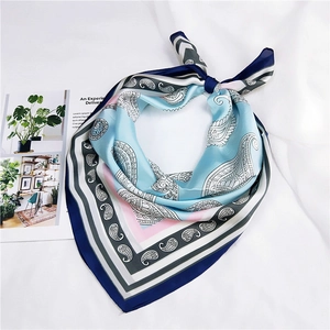 Détail d'un foulard carré en satin à motif paisley aux tons bleu clair et rose