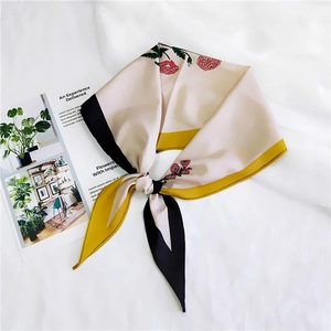 Close-up of silk-feel floral scarf with yellow border and lip prints on white backdrop