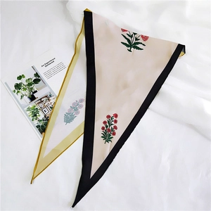 Detail of triangle silk scarf with floral print and black yellow borders on white fabric