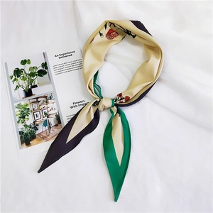 Detail of floral print silk scarf with green and red patterns on white fabric background