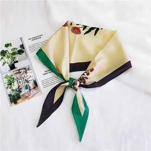 Close-up of silk square scarf with floral print and geometric border on white cloth