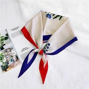 Detail of silk scarf with floral patterns and contrast borders on textured background