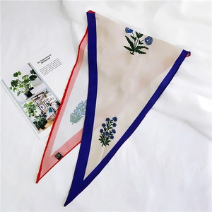 Detail of 100% silk diamond scarves featuring elegant blue floral prints and silk labels