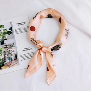 Close-up of knotted silk scarf with leaf print on white fabric next to a magazine