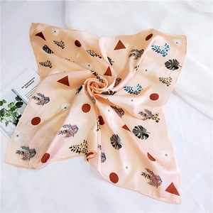 Detailed close-up of pink silk-like scarf with leaf prints and geometric patterns