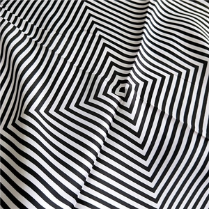 Detailed close-up of silk scarf showing black and white geometric spiral pattern