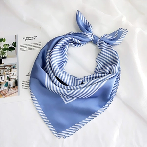 Detail of blue and white striped silk square scarf on white textured background
