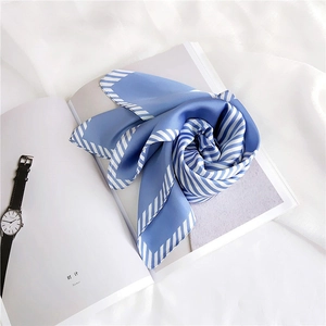 Macro shot of sky blue satin square scarf with white diagonal stripe border and silky texture
