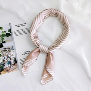 Close-up of champagne and white striped silk scarf tied elegantly on a minimal background