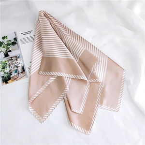Detailed view of beige and white striped silk scarf folded on a white fabric background