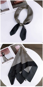 Detail of a black and gold striped silk scarf tied and flat laid on a white table