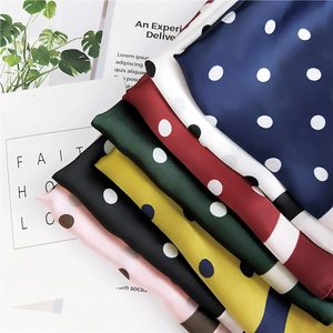 Vue à plat de foulards en soie à pois colorés en bleu marine, rouge et rose vif
