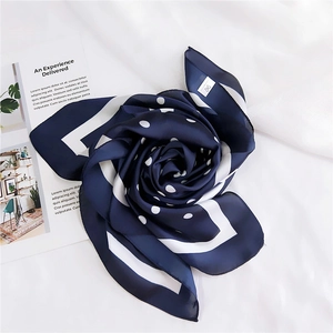 Gros plan d'un foulard en soie bleu marine à pois plié en forme de rose avec logo