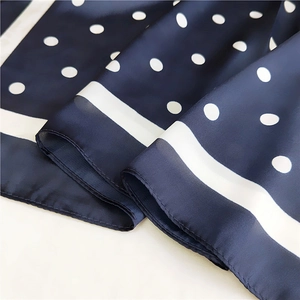 Détail macro du foulard en soie bleu marine à pois montrant la texture satinée lisse