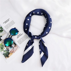 Gros plan d'un foulard en soie bleu marine à pois avec des lunettes de soleil élégantes