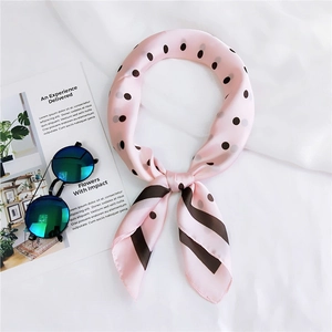 Mise à plat d'un foulard en soie rose clair à pois avec lunettes sur un magazine chic