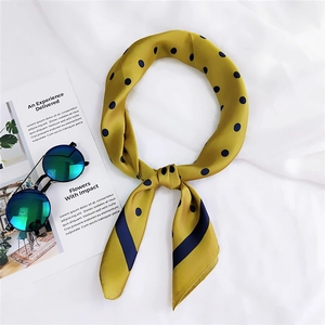 Gros plan d'un foulard en soie à pois jaunes avec bordure noire sur un tissu blanc