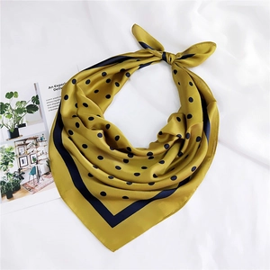 Détail d'un foulard en soie jaune moutarde à pois bleus avec bordure contrastée