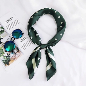 Gros plan d'un foulard en soie vert à pois noué en boucle sur un magazine de mode