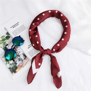Gros plan d'un foulard en soie bordeaux à pois avec des accessoires de mode chic
