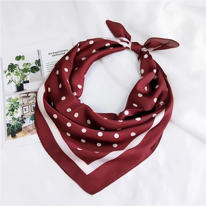 Détail d'un carré de soie rouge foncé à pois avec bordure rayée blanche et texture douce