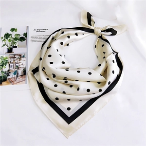 Détail d'un foulard carré en soie à pois avec bordure noire noué avec style