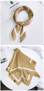 Détail d'un foulard en soie jaune à pois, noué et posé sur une surface blanche