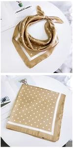 Détail d'un foulard en soie jaune doré à pois avec bordure blanche sur une table blanche