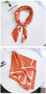 Détail du foulard en soie orange à pois blancs avec bordure et nœud de style élégant