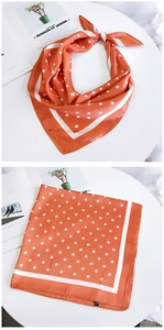 Détail du foulard en soie orange à pois montrant le style noué et le motif à plat