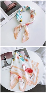 Detail of square silk scarf showing tropical flamingo and cactus patterns on a white base