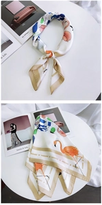 Detail of silk scarf with flamingo print and champagne geometric patterns on white desk