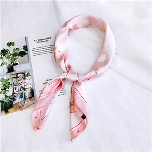 Detail of pink silk twilly scarf with flamingo and star patterns on white fabric