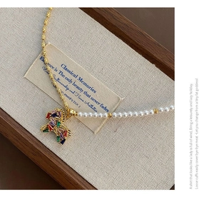 Close-up of elegant gold necklace with colorful zircon pony pendant and white pearls