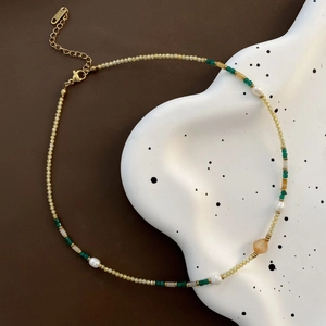 Elegant emerald and pearl beaded necklace with K18 gold clasp on a ceramic tray