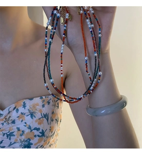 Gros plan d'un collier de perles colorées et d'un bracelet en jade gris élégant