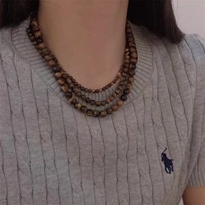 Détail d'un collier de perles en oeil de tigre multicouche sur pull en maille