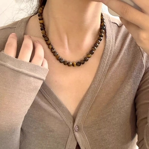 Gros plan du collier en perles d'oeil de tigre avec texture marron porté en choker