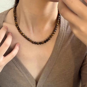 Gros plan d'un collier en perles d'œil de tigre avec texture de pierre naturelle