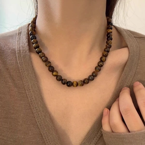 Collier de perles en œil de tigre avec textures brunes naturelles porté par un modèle