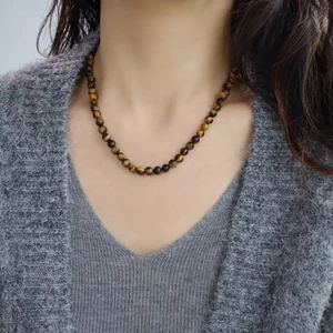 Collier en perles d'oeil de tigre avec pierres naturelles sur cardigan gris élégant