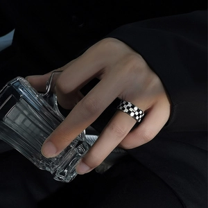 Detail shot of a black and white checkered gold-plated steel ring on a model's finger