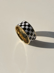 Macro detail of the 18K gold plated titanium ring with black and white checkered enamel