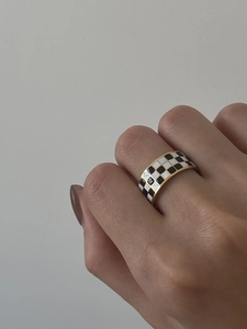 Detail of checkered black and white enamel ring in 18K gold plated titanium steel