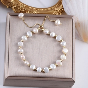 Detalle de pulsera de perlas barrocas con cuentas doradas en un estuche de joyas