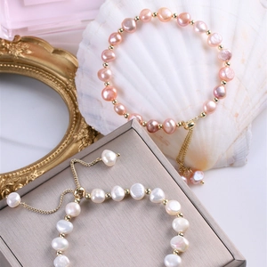 Detalle de pulseras de perlas barrocas con cadenas doradas ajustables sobre una concha