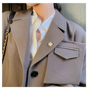 Vue détaillée d'une broche trèfle à quatre feuilles sur le revers d'un blazer