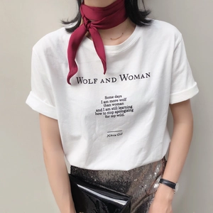 Close-up of red silk scarf accent styled with a white graphic t-shirt and gold necklace