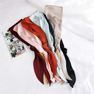 Close-up of assorted silk satin skinny scarves in various colors with a glossy finish