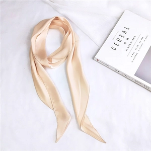 Close-up of a champagne satin silk scarf ribbon elegantly draped over a magazine background